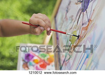 Stock Image - A child painting on an easel, close-up of hand. Fotosearch