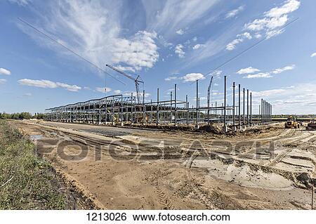 Stock Photograph - A crane towering above a construction frame at a construction site. Fotosearch