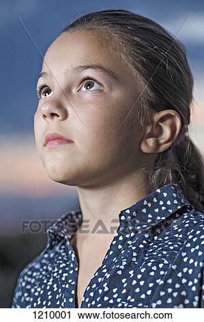 Stock Image - A girl looking up contemplatively, close-up. Fotosearch