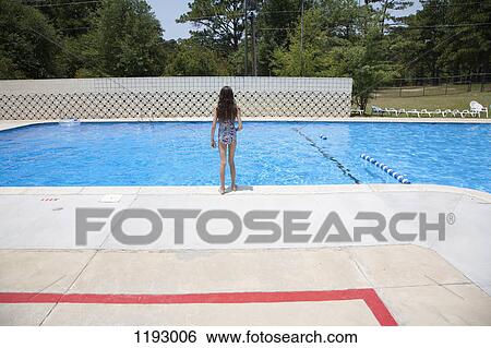 Stock Photograph - A girl standing at the edge of a swimming pool. Fotosearch