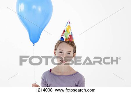 Stock Photo - A girl wearing a party hat and holding a balloon, close-up. Fotosearch