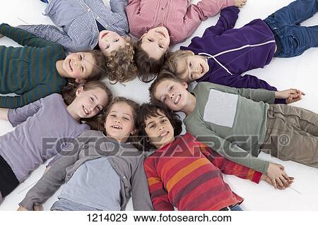 Stock Photo - A group of kids lying on their backs in a circle, heads touching. Fotosearch