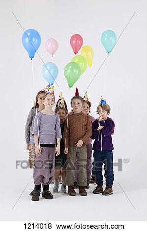 A group of kids wearing party hats and holding balloons View Large Photo Image Stock Photo - A group of kids wearing party hats and holding balloons. Fotosearch