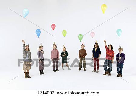 A group of mostly bored looking kids holding balloons and wearing party hats View Large Photo Image Stock Image - A group of mostly bored looking kids holding balloons and wearing party hats. Fotosearch