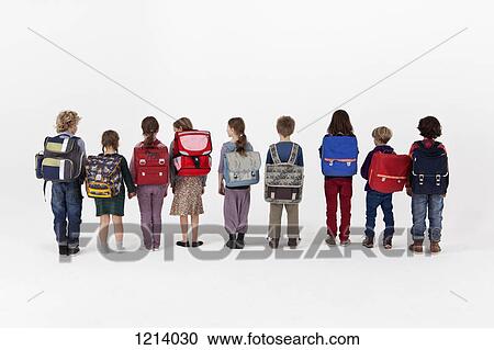 Stock Image - A group of school children wearing backpacks and standing in a row, rear view. Fotosearch