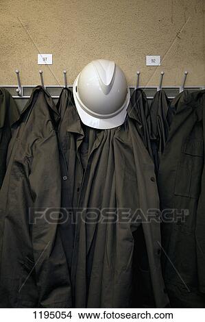 Picture - A hard hat and uniforms hanging on hooks. Fotosearch