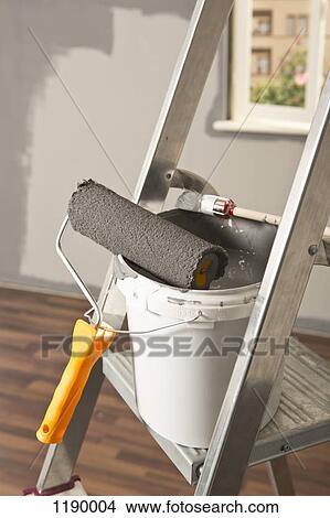 A ladder with paint roller and paintbrush leaning on paint bucket View Large Photo Image Picture - A ladder with paint roller and paintbrush leaning on paint bucket. Fotosearch