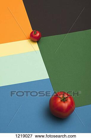 A large tomato and a small tomato placed on a multi colored geometric pattern View Large Photo Image Stock Photo - A large tomato and a small tomato placed on a multi colored geometric pattern. Fotosearch