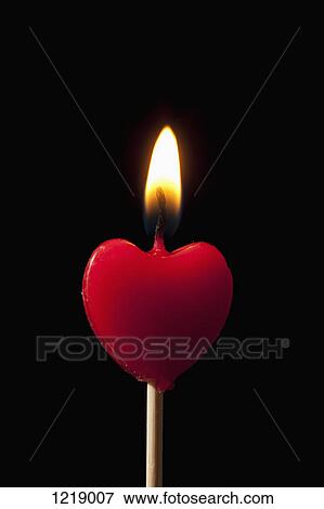 A lit heart shaped candle on a stick View Large Photo Image Stock Photo - A lit heart shaped candle on a stick. Fotosearch