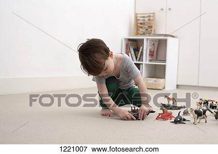 A little boy playing with some toy animal figurines on the floor of his bedroom View Large Photo Image Stock Photo - A little boy playing with some toy animal figurines on the floor of his bedroom. Fotosearch