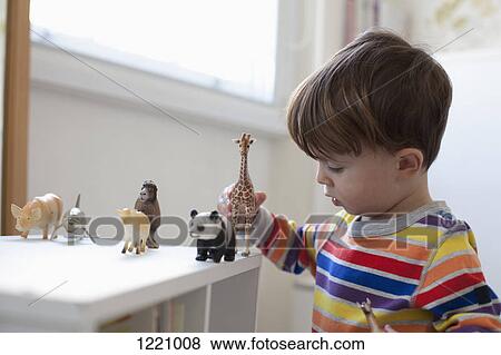 Stock Photo - A little boy playing with some toy animal figurines on the floor of his bedroom. Fotosearch