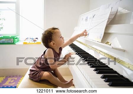 A little boy sitting at a piano reaching out with curiosity for the sheet music View Large Photo Image Stock Image - A little boy sitting at a piano reaching out with curiosity for the sheet music. Fotosearch
