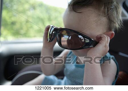 A little boy sitting in a stationary car playing with sunglasses View Large Photo Image Stock Photography - A little boy sitting in a stationary car playing with sunglasses. Fotosearch