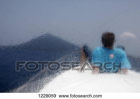 A man reclining on a boat looking at Krakatau volcano, rear view, seen thru window View Large Photo Image Stock Photo - A man reclining on a boat looking at Krakatau volcano, rear view, seen thru window. Fotosearch