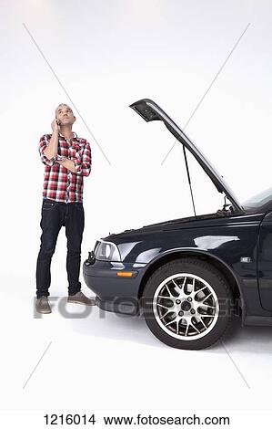 A man standing next to broke down car, using a cell phone and looking impatient View Large Photo Image Picture - A man standing next to broke down car, using a cell phone and looking impatient. Fotosearch