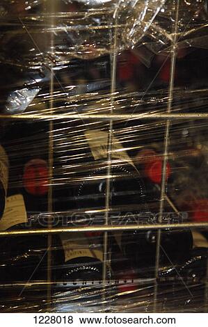 Stock Photo - A metal crate filled with stacked red wine bottles and wrapped in plastic wrap. Fotosearch