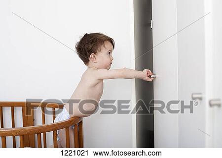 A mischievous toddler reaching out to open a closet door from his crib View Large Photo Image Stock Image - A mischievous toddler reaching out to open a closet door from his crib. Fotosearch