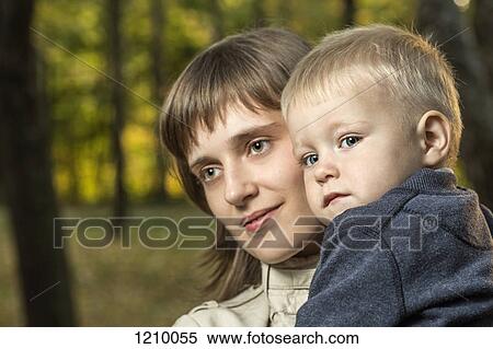 Stock Photography - A mother holding her young son and looking away serenely. Fotosearch