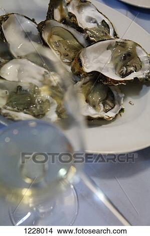 A plate of raw oysters and a glass of white wine, close-up View Large Photo Image Picture - A plate of raw oysters and a glass of white wine, close-up. Fotosearch