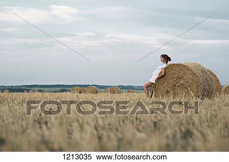 A pregnant woman leaning against a bale of hay in a remote setting View Large Photo Image Stock Photography - A pregnant woman leaning against a bale of hay in a remote setting. Fotosearch
