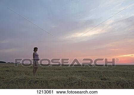 A pregnant woman standing in a remote field under a dramatic sky View Large Photo Image Stock Image - A pregnant woman standing in a remote field under a dramatic sky. Fotosearch