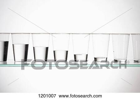 A row of glasses with varying amounts of water descending from full to empty View Large Photo Image Stock Photo - A row of glasses with varying amounts of water descending from full to empty. Fotosearch