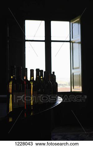 A row of various wine bottles on a bar counter near an open window View Large Photo Image Stock Image - A row of various wine bottles on a bar counter near an open window. Fotosearch