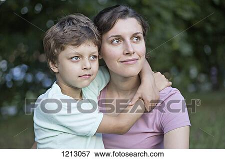 Stock Photo - A serene mother and son looking away thoughtfully. Fotosearch