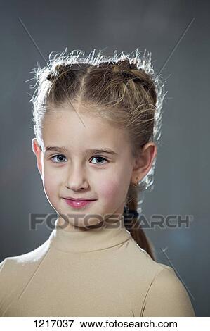 Stock Photo - A serene young girl with a fashionable braided hairstyle and wearing earrings. Fotosearch