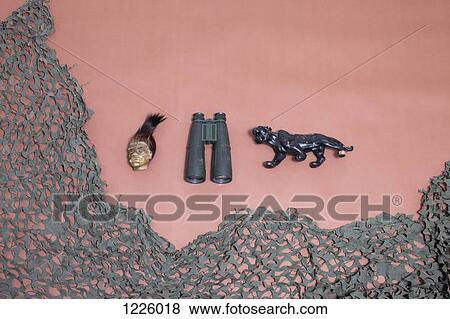 Stock Photo - A shrunken head, binoculars, a jaguar and camouflage netting. Fotosearch