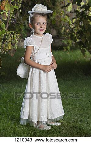A smiling young girl dressed elegantly in a white dress, hat and purse View Large Photo Image Stock Image - A smiling young girl dressed elegantly in a white dress, hat and purse. Fotosearch