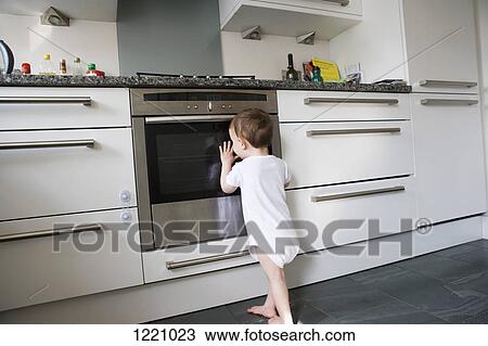 A toddler leaning on an oven door, peeking inside View Large Photo Image Stock Image - A toddler leaning on an oven door, peeking inside. Fotosearch