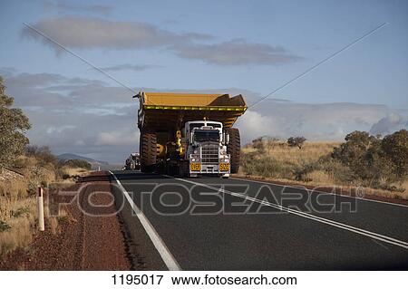 Stock Photo - A truck with a wide load driving on a desert highway. Fotosearch