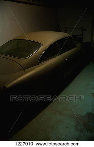 Stock Image - A vintage car parked in a dark garage. Fotosearch