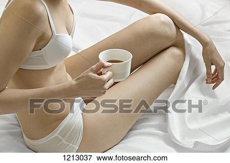 A woman in her underwear drinking tea in bed, neck down View Large Photo Image Stock Photo - A woman in her underwear drinking tea in bed, neck down. Fotosearch