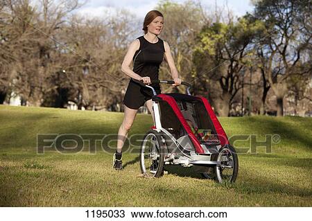 A woman jogging in a park and pushing a baby stroller View Large Photo Image Stock Image - A woman jogging in a park and pushing a baby stroller. Fotosearch