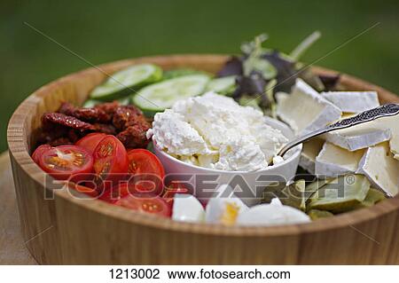 Stock Image - A wooden salad bowl filled with various vegetables and cheeses. Fotosearch
