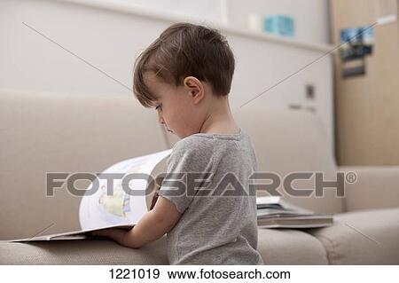 Stock Photo - A young boy looking at a picture book. Fotosearch
