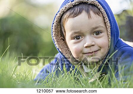 Stock Photo - A young boy wearing a hooded jacket in the grass. Fotosearch
