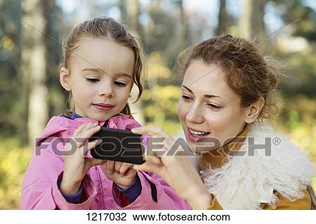 Stock Image - A young daughter showing her Mom something on a smart phone. Fotosearch