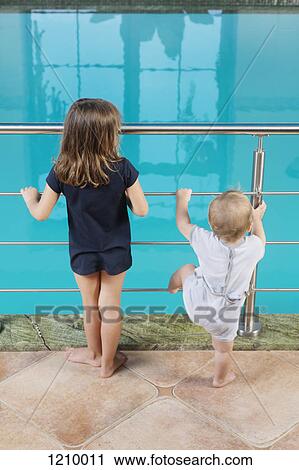 A young girl and her toddler brother standing side by side looking at a swimming pool View Large Photo Image Stock Image - A young girl and her toddler brother standing side by side looking at a swimming pool. Fotosearch