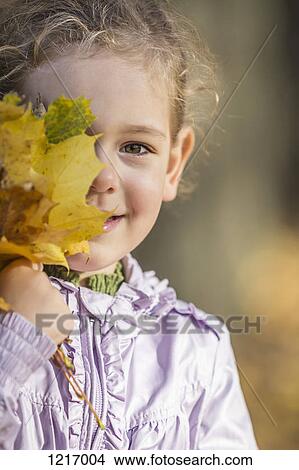 A young girl covering one eye with a bunch of autumn leaves View Large Photo Image Picture - A young girl covering one eye with a bunch of autumn leaves. Fotosearch