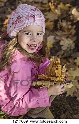 Stock Photo - A young girl holding a bunch of autumn leaves. Fotosearch
