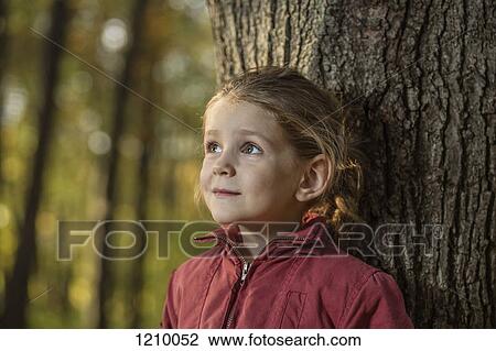 A young girl leaning against a tree trunk View Large Photo Image Stock Image - A young girl leaning against a tree trunk. Fotosearch