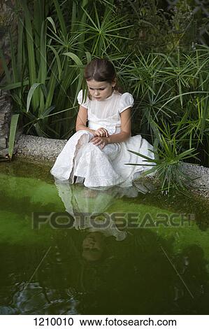 A young girl looking curiously into pond water View Large Photo Image Stock Image - A young girl looking curiously into pond water. Fotosearch