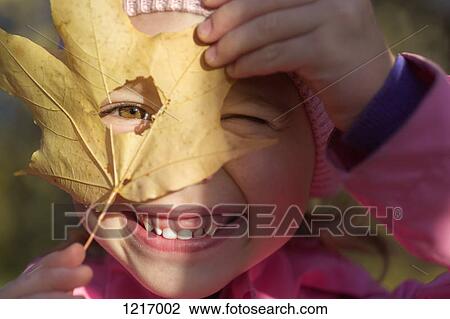 A young girl looking through a hole in a leaf she's holding up to her face View Large Photo Image Stock Image - A young girl looking through a hole in a leaf she's holding up to her face. Fotosearch