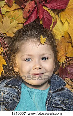 A young girl lying amongst autumn leaves View Large Photo Image Stock Photo - A young girl lying amongst autumn leaves. Fotosearch