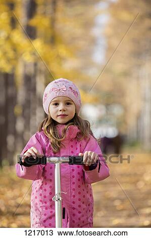 A young girl standing on a push scooter View Large Photo Image Stock Image - A young girl standing on a push scooter. Fotosearch