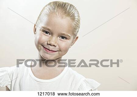 Stock Photo - A young girl with her head cocked smiling serenely. Fotosearch