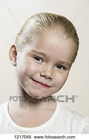 Stock Photography - A young girl with her head cocked smiling serenely. Fotosearch
